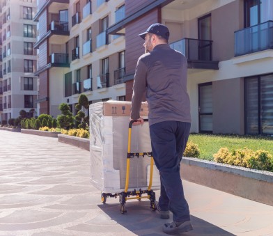 Delivery person using hand truck to deliver big and bulky packages.